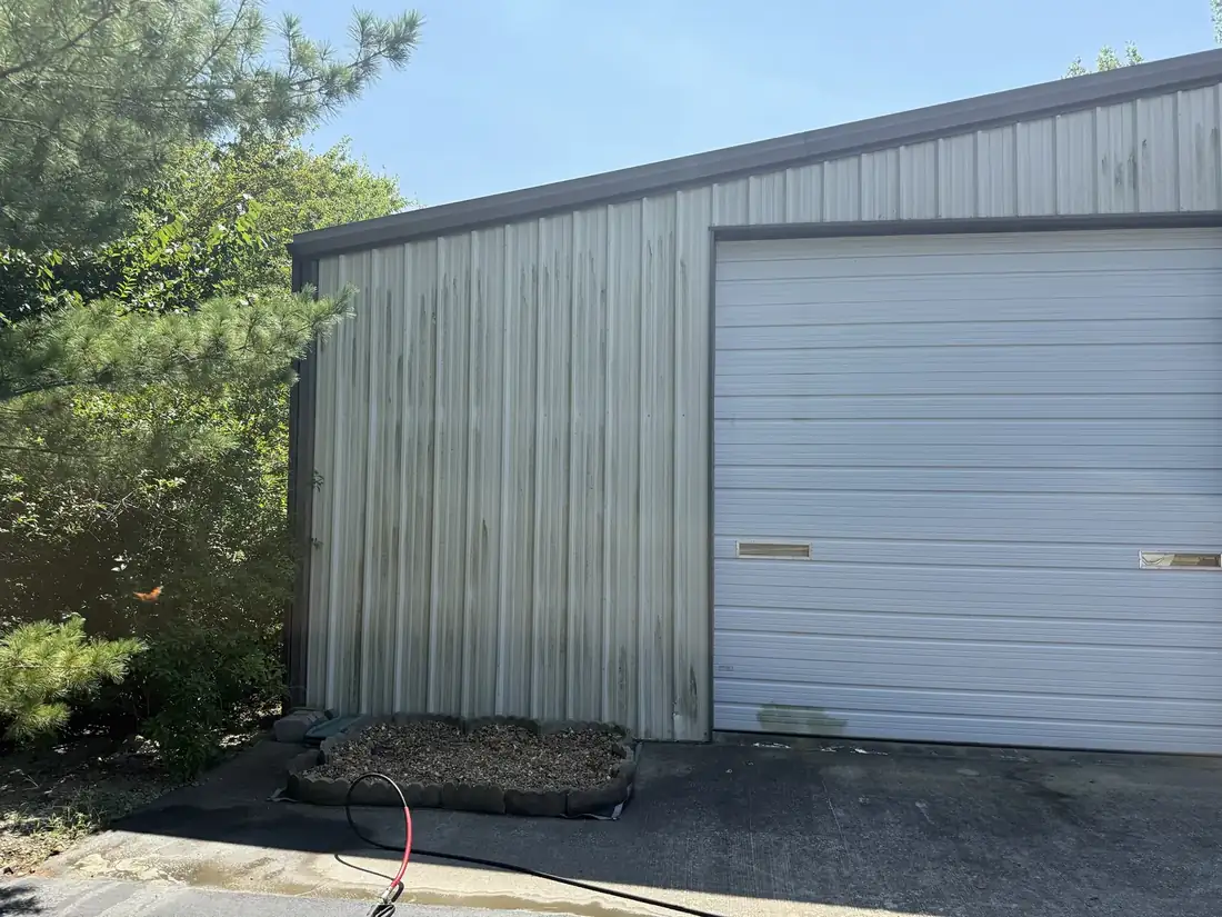 Metal building wall with green algae streaks before washing
